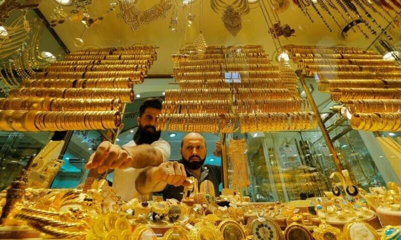 Gold dips on firm dollar, but hopes of less aggressive Fed cap decline