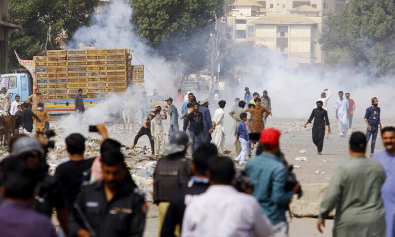 Supporters (R) of former prime minister Imran Khan try to stop riot police scuffle outside Khan’s house to prevent officers from arresting him, in Lahore – AFP