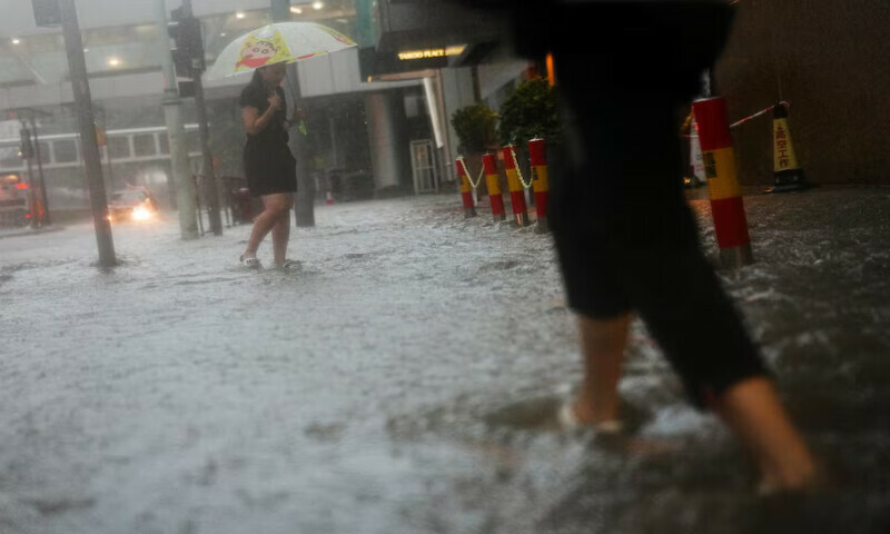 Pedestrians walk past a flooded area in Hong Kong, China, on Thursday. – Reuters