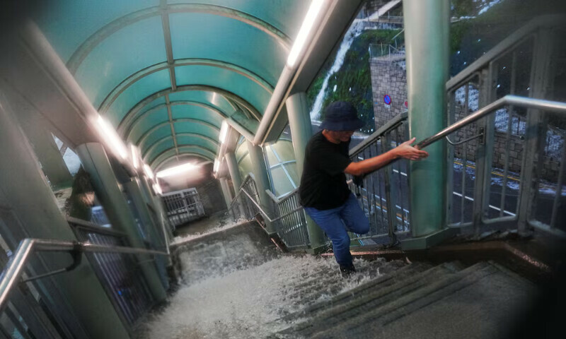 A pedestrian walks up a flooded stairs outside a hospital in Hong Kong, China, on Tuesday. – Reuters