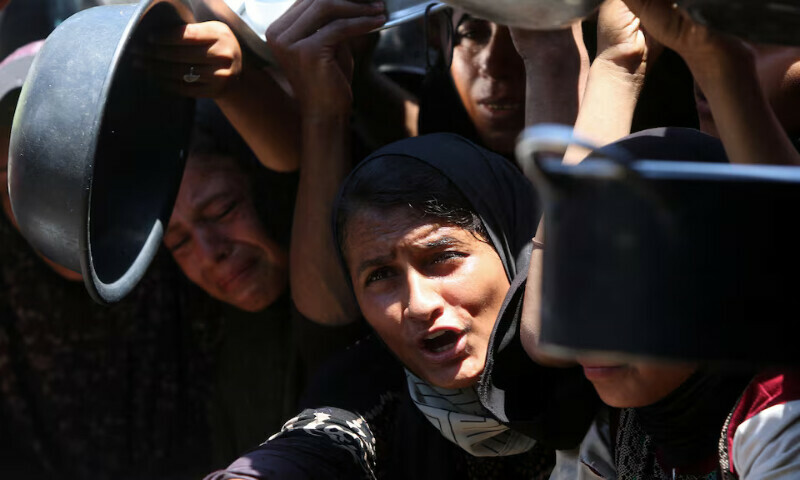 Palestinians wait to receive food amid a hunger crisis in Khan Younis, southern Gaza Strip. – Reuters