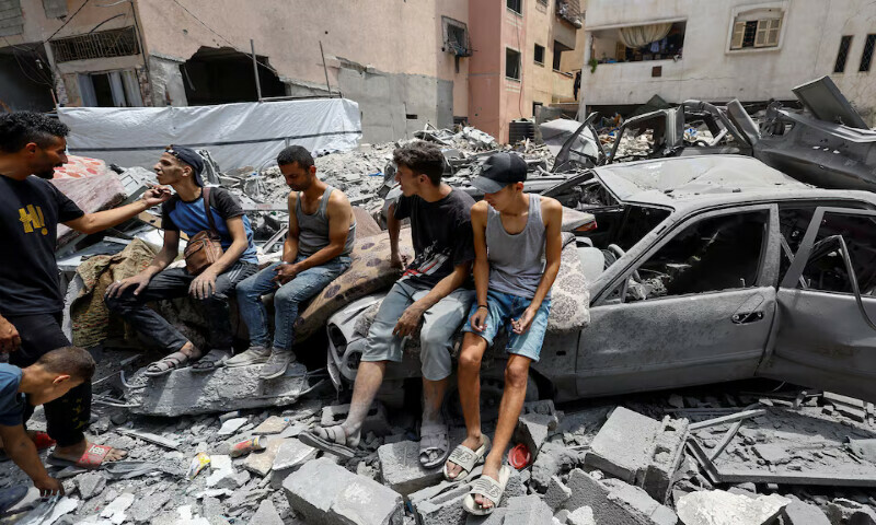 Palestinians gather at the site of an Israeli strike on a house in Gaza City. – Reruters
