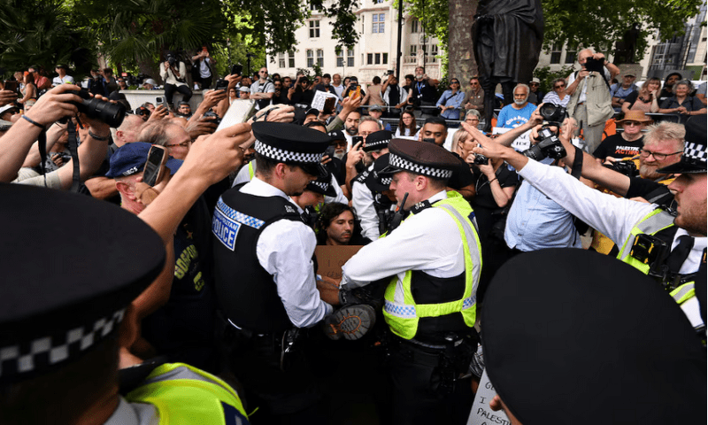 Police officers detain a demonstrator, as people hold placards that read “I oppose genocide, I support Palestine Action” during a rally organised by Defend Our Juries, challenging the British government’s proscription of “Palestine Action” under anti-terrorism laws, in Parliament Square, in London, on August 9, 2025. Reuters
