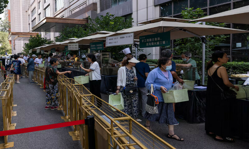 People gather near food stalls outside Beiyuan Grand Hotel in Beijing, China. – Reuters