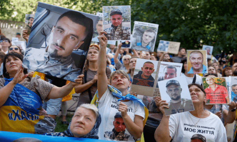 People hold portraits of their relatives, Ukrainian prisoners of war, hoping they will be recognised by other prisoners of war, who return after a swap in an undisclosed location in Ukraine, on August 14, 2025. Reuters