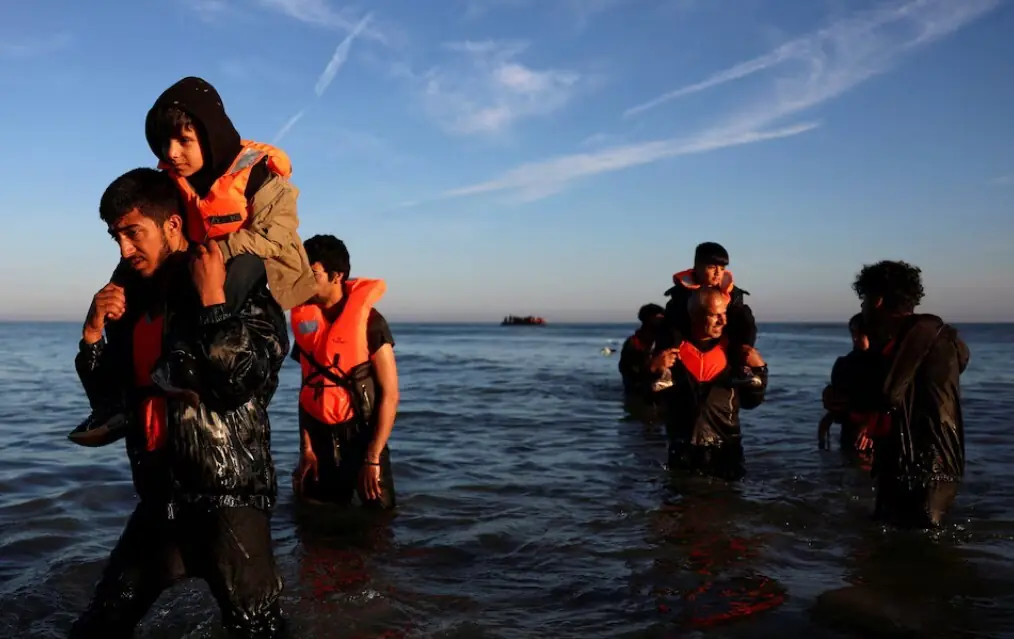 Migrants wade through the sea after failing to board an inflatable dinghy in an attempt to leave the coast of northern France to cross the English Channel to reach Britain, from the beach of Petit-Fort-Philippe in Gravelines, near Calais, France, August 25, 2025. REUTERS