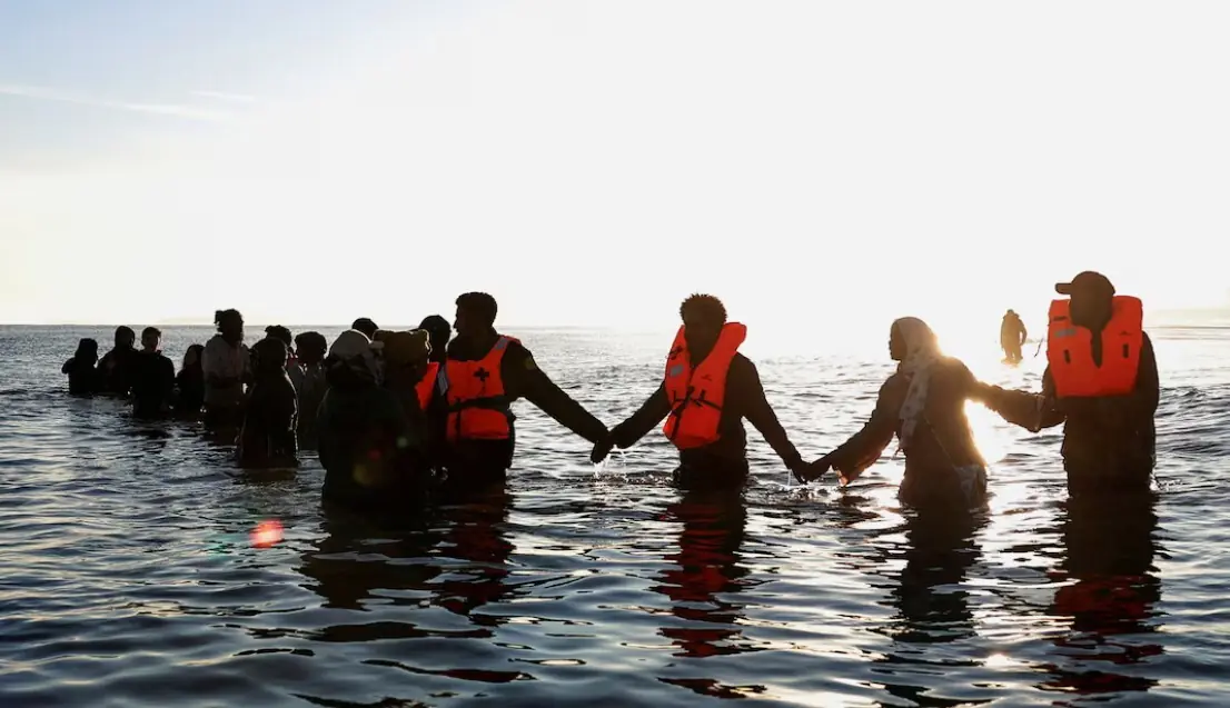 Migrants wade through the sea in an attempt to board an inflatable dinghy leaving the coast of northern France to cross the English Channel to reach Britain, from the beach of Petit-Fort-Philippe in Gravelines, near Calais, France, August 25, 2025. REUTERS