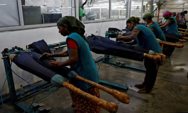 Workers use sandpaper on jeans to fade colour in a garment manufacturing unit on the outskirts of Ahmedabad, India. – Reuters