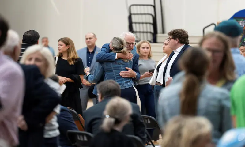 Minnesota Governor Tim Walz hugs a fellow guest during a prayer vigil at Academy of Holy Angels following a shooting earlier in the day at Annunciation Church in Minneapolis, in Richfield, Minnesota. – Reuters