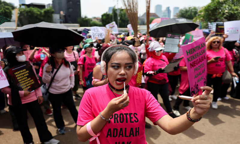 A woman uses a lip tint while attending a protest against lawmakers’ perks and police brutality outside the Indonesian parliament building in Jakarta on Wednesday. – Reuters