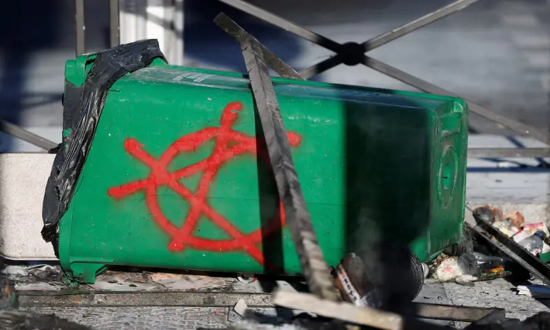 A symbol for anarchism is seen painted on a damaged garbage bin installed on a street to block the traffic during a day of protests in Paris, France, on Wednesday. – Reuters