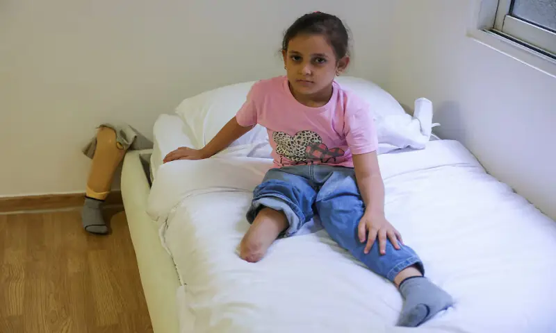 Aya Abdallah, a Gazan child who lost her right leg in an Israeli strike, sits on a bed in Beirut, Lebanon. – Reuters