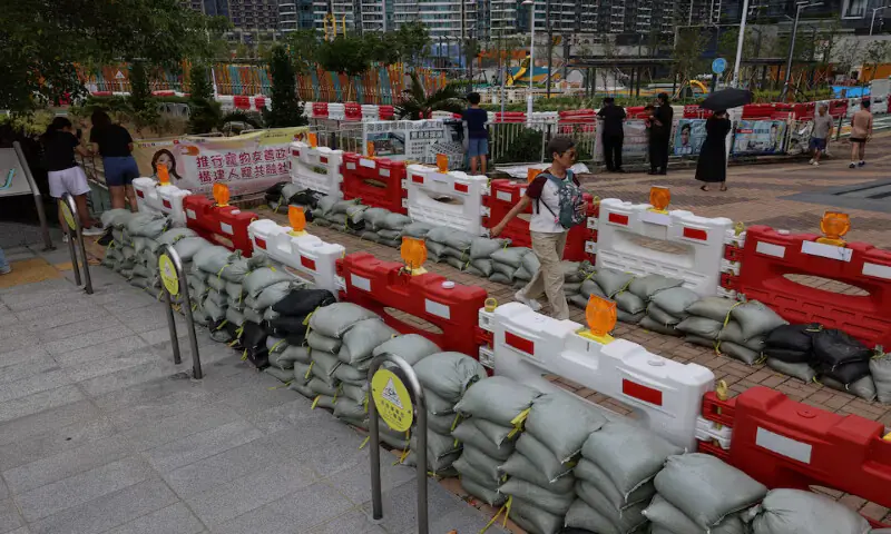 Residents walk past sandbags placed to prevent flooding from Super Typhoon Ragasa in Hong Kong on Tuesday. – Reuters