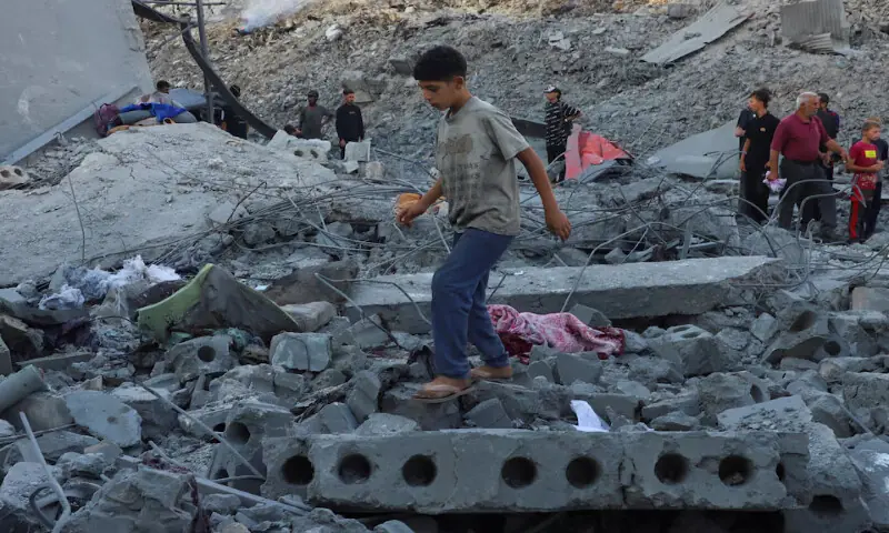 Palestinians inspect the site of deadly Israeli strikes on a building where displaced people were taking shelter in Gaza City. – Reuters