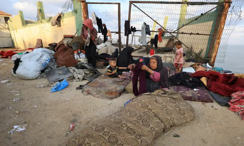 A displaced Palestinian family due to an Israeli military operation sits on the roadside in the central Gaza Strip. – Reuters