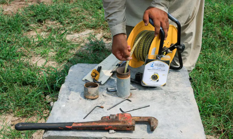 Zaheer, an employee of the Punjab Irrigation Department, uses a dipmeter to check the groundwater level at a borehole in Babakwal, Sheikhupura District in Punjab. – Reuters