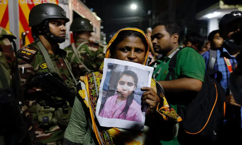 A relative mourns while holding a picture of a missing girl following a fire that broke out at a garment factory and a chemical warehouse in Dhaka, Bangladesh, on Tuesday. – Reuters