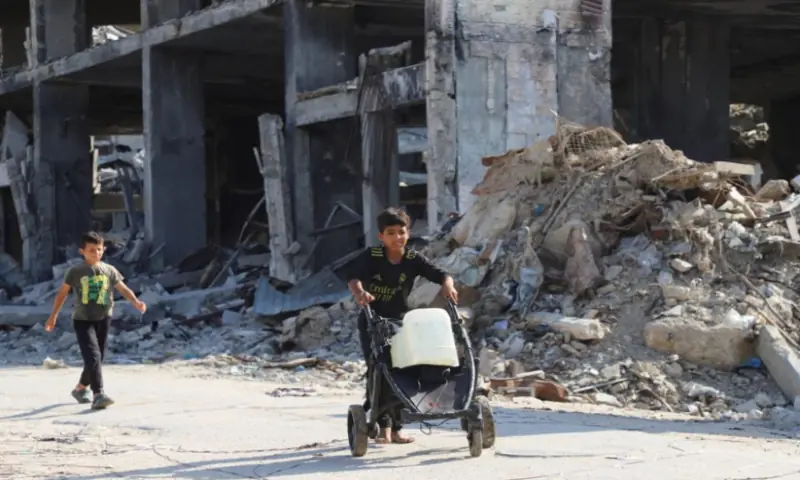Displaced Palestinian children walk, as one of them moves a cart loaded with water containers, amid a ceasefire between Israel and Hamas, in Gaza City, on October 19, 2025. Reuters