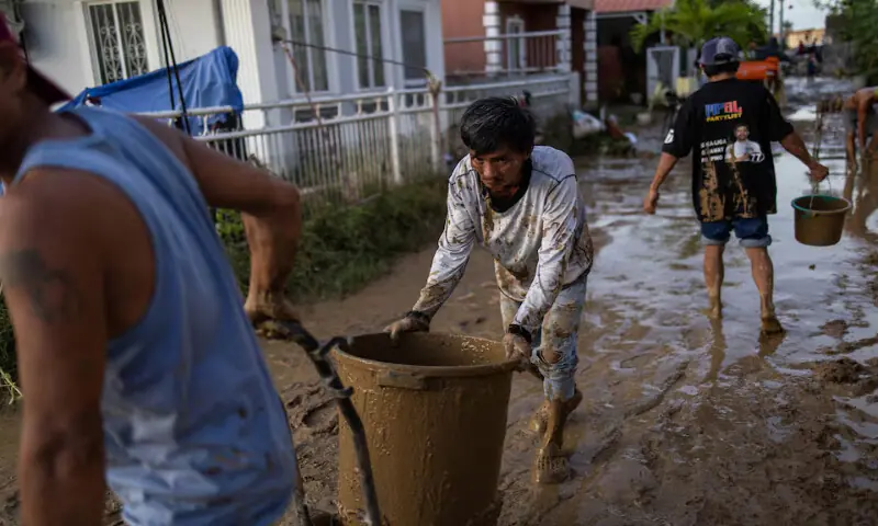 People push and carry buckets of mud from inside homes after heavy flooding brought by Typhoon Kalmaegi in Cotcot, Liloan, Philippines, on Wednesday. – Reuters