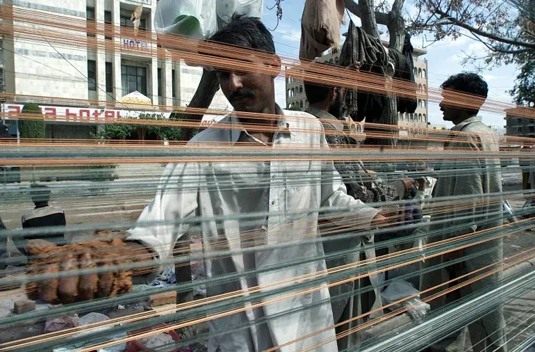 ایک شخص مانجھا بنانے کے لیے ڈور پر شیشے کے پاؤڈر سے بنا پیسٹ لگا رہا ہے (تصویر: رائٹرز)