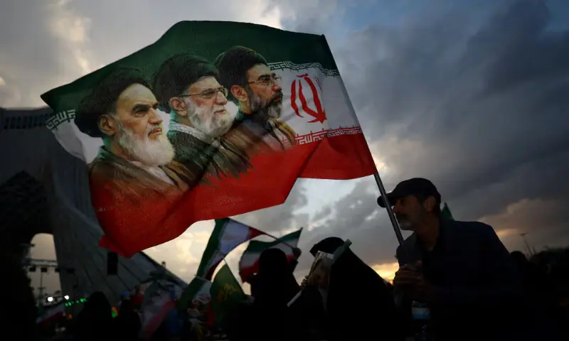 A man holds a flag with a picture of late leaders Ayatollah Ruhollah Khomeini, Ayatollah Ali Khamenei and Iran&rsquo;s new Supreme Leader Mojtaba Khamenei, during a rally in Tehran, Iran. &ndash; Reuters