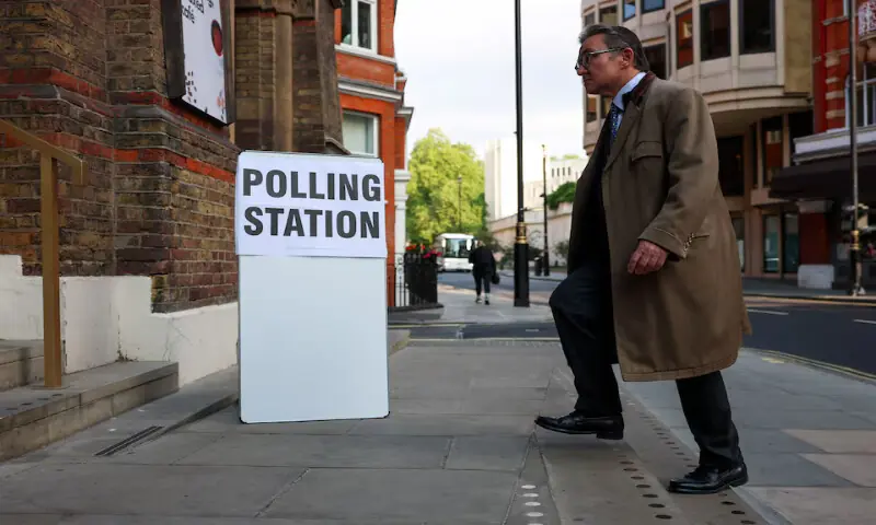 A man walks next to a sign outside a polling station during local elections in London, on Thursday. &ndash; Reuters