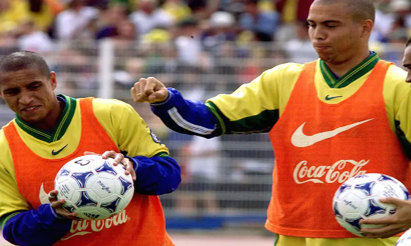 Brazilian striker Ronaldo jokes with team mate Roberto Carlos while holding Tricolore soccer balls in training at the 1998 World Cup. – Reuters
