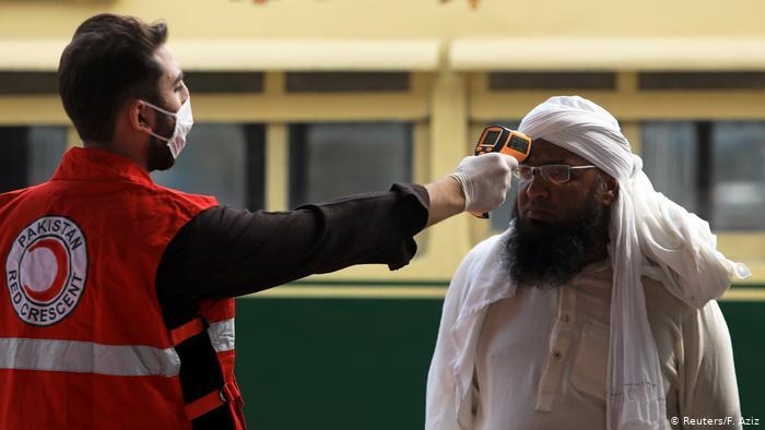 A health worker is checking temperature of a passenger at railway station to filter out potential COVID infected travellers. File photo