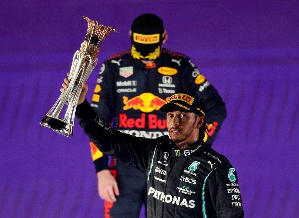 Mercedes' Lewis Hamilton celebrates with the trophy on the podium after winning the race as second placed Red Bull's Max Verstappen looks dejected. Reuters