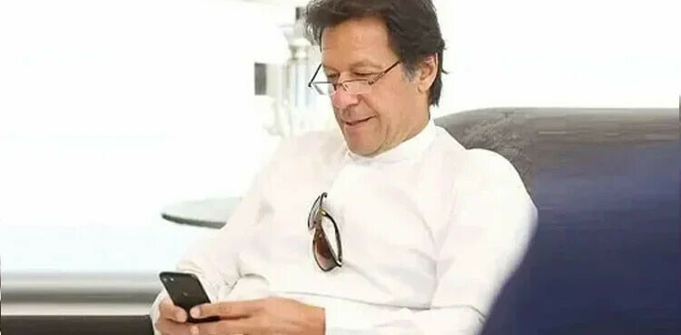 PTI chief Imran Khan using a cell phone. Photo via social media.