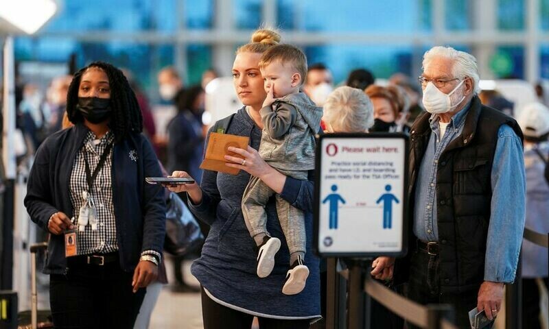 Masked and unmasked travellers line up at a security checkpoint at the Ronald Reagan Washington National Airport in Arlington, Virginia on April 19, 2022. Reuters/File