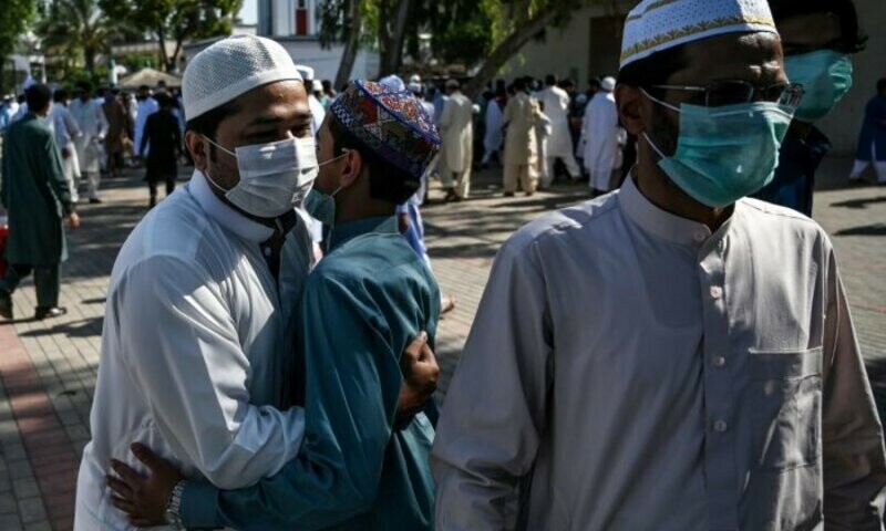 People wearing facemasks exchange greetings after offering Eidul Fitr prayers despite concerns over the spread of the Covid-19 at the Eidgah Sharif Darbar in Rawalpindi on May 24, 2020. AFP