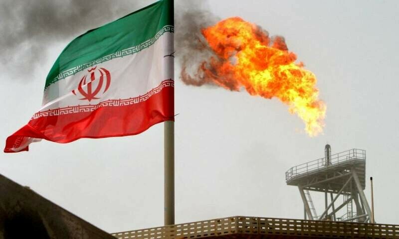 A gas flare on an oil production platform is seen alongside an Iranian flag in the Gulf July 25, 2005. REUTERS