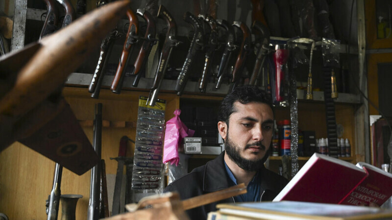 In this photograph taken on January 4, 2023, an arms dealer Muhammad Jahanzeb reads a book at his shop in Darra Adamkhel town, some 35 kilometres (20 miles) south of Peshawar. AFP