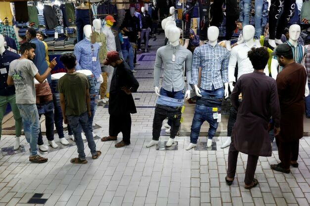 People look at menswear in shops at a market, ahead of Eid al-Fitr celebrations in Karachi, Pakistan April 19, 2023. REUTERS/Akhtar Soomro