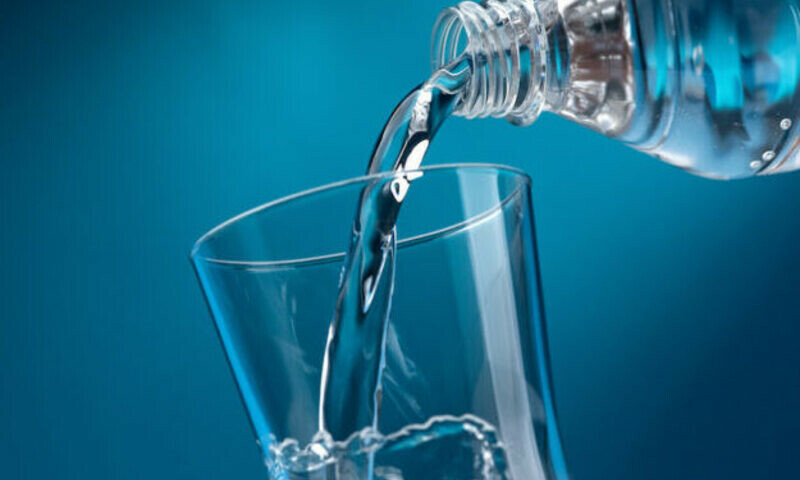 Pouring fresh mineral water from a bottle into a glass, hydration and diet concept