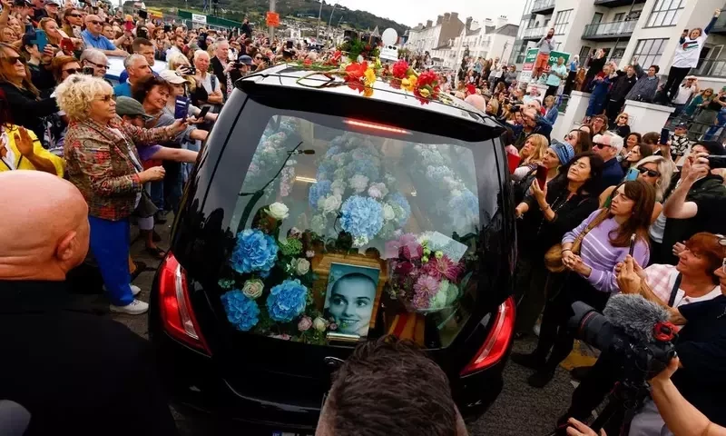 A hearse carrying the coffin of late Irish singer Sinead O&rsquo;Connor passes by during her funeral procession where fans line the street to say their last goodbye to her, in Bray, Ireland, August 8, 2023. REUTERS