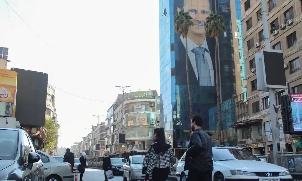 People walk near a poster depicting Syria’s President Bashar al-Assad in Damascus, after last week’s rebel seizure of Aleppo marked the biggest offensive for years, Syria December 5, 2024. Photo via Reuters People walk near a poster depicting Syria’s President Bashar al-Assad in Damascus, after last week’s rebel seizure of Aleppo marked the biggest offensive for years, Syria December 5, 2024. Photo via Reuters