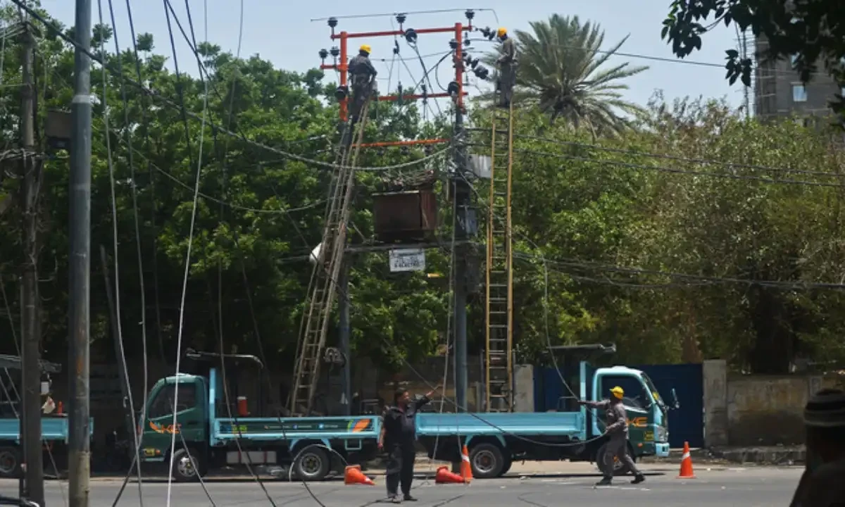 Men work on electric pylons along the roadside in Karachi on May 30, 2021. AFP Men work on electric pylons along the roadside in Karachi on May 30, 2021. AFP