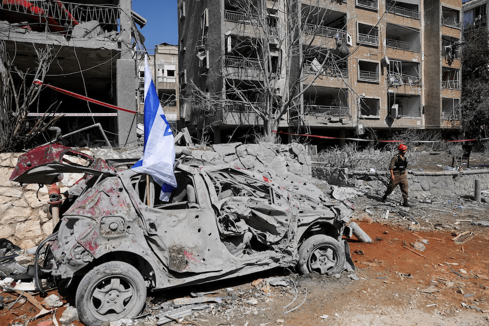 A rescuer walks next to a damaged vehicle at an impact site in Ramat Gan, Israel, following a missile attack from Iran. – Reuters A rescuer walks next to a damaged vehicle at an impact site in Ramat Gan, Israel, following a missile attack from Iran. – Reuters