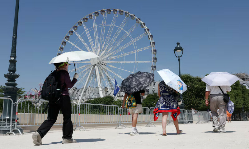 Tourists, holding an umbrella to protect themselves from the sun, walk past a Ferris wheel in the Tuileries Garden  in Paris, France, on Wednesday. – Reuters Tourists, holding an umbrella to protect themselves from the sun, walk past a Ferris wheel in the Tuileries Garden  in Paris, France, on Wednesday. – Reuters
