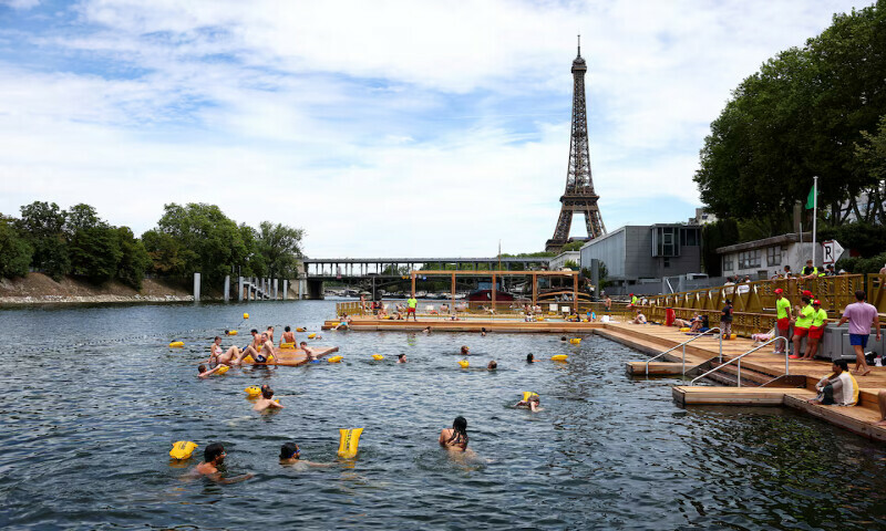 People swim in the River Seine, with the Eiffel tower in the background, at the Grenelle site, opened to swimmers marking the first public bathing session in the capital’s historic waterway, in Paris, France, on Saturday. – Reuters People swim in the River Seine, with the Eiffel tower in the background, at the Grenelle site, opened to swimmers marking the first public bathing session in the capital’s historic waterway, in Paris, France, on Saturday. – Reuters