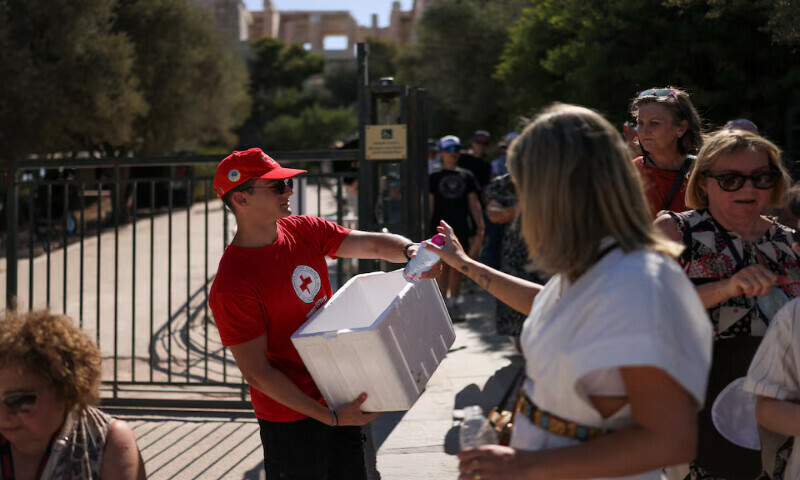 A volunteer hands over water bottles to visitors of the Acropolis archaeological site in Athens, Greece. – Reuters A volunteer hands over water bottles to visitors of the Acropolis archaeological site in Athens, Greece. – Reuters