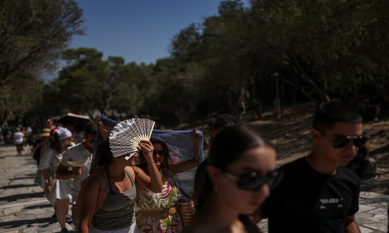 A woman covers herself with a fan while queuing to visit the Acropolis in Athens, Greece. – Reuters A woman covers herself with a fan while queuing to visit the Acropolis in Athens, Greece. – Reuters