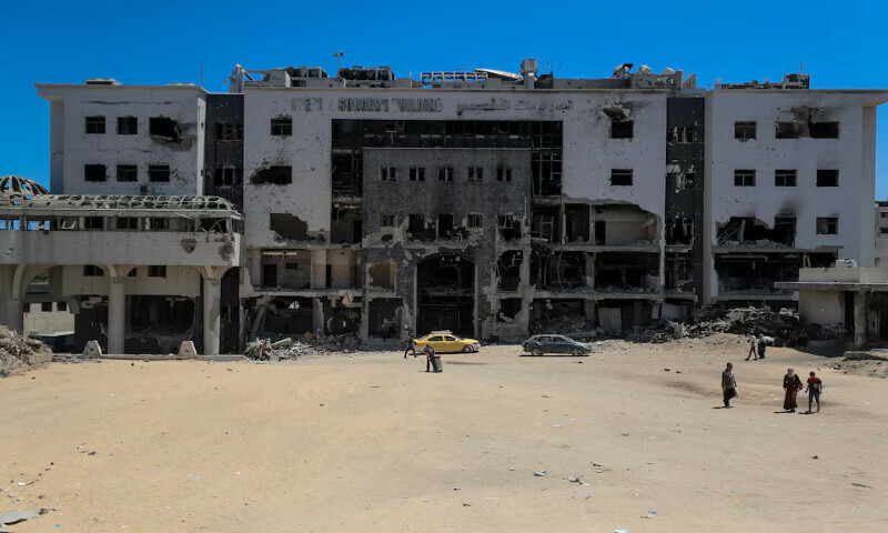 Palestinians walk next to a damaged building of Al Shifa hospital, which is at risk of shutting down due to the Israeli blockade, in Gaza City. — Reuters Palestinians walk next to a damaged building of Al Shifa hospital, which is at risk of shutting down due to the Israeli blockade, in Gaza City. — Reuters
