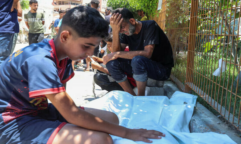 A Palestinian man, with his son, mourns beside the body of his other son, who was killed by Israeli fire while seeking aid near a distribution point in Rafah, at Nasser Hospital in Khan Younis, southern Gaza Strip on Saturday. – Reuters