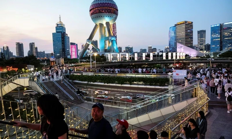 People walk on a pedestrian bridge at Lujiazui financial district in Shanghai, China, July 14, 2025. REUTERS