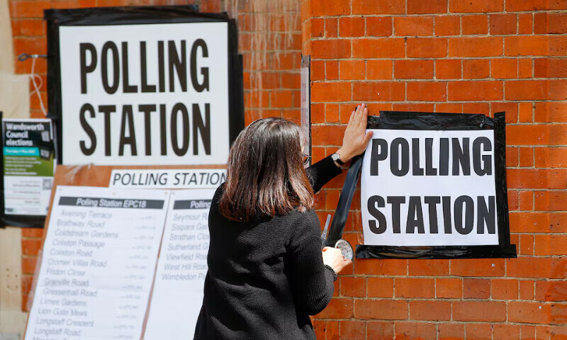 A woman attaches a sign on the wall of a polling station in London, Britain. – Reuters file A woman attaches a sign on the wall of a polling station in London, Britain. – Reuters file
