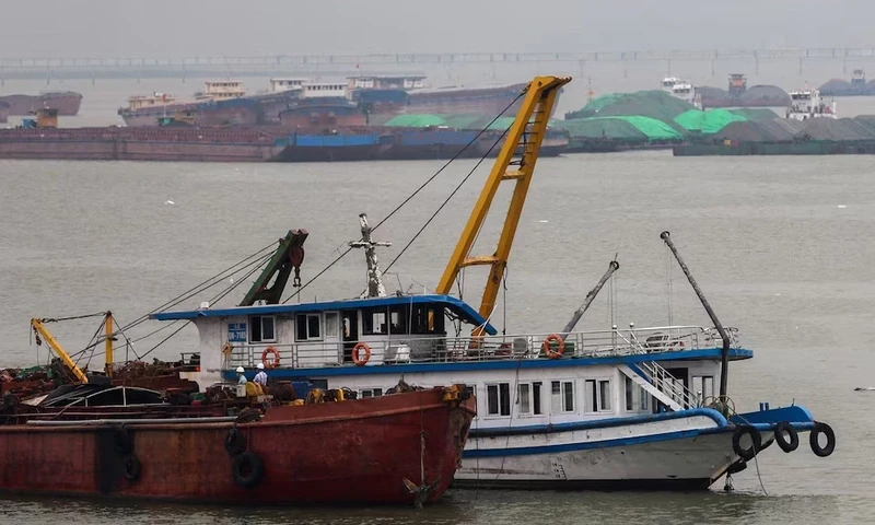 A tourist boat (in white) that capsized in an accident which killed dozens and left several people still missing, is towed back to the port in Halong Bay, Quang Ninh province, Vietnam, July 20, 2025