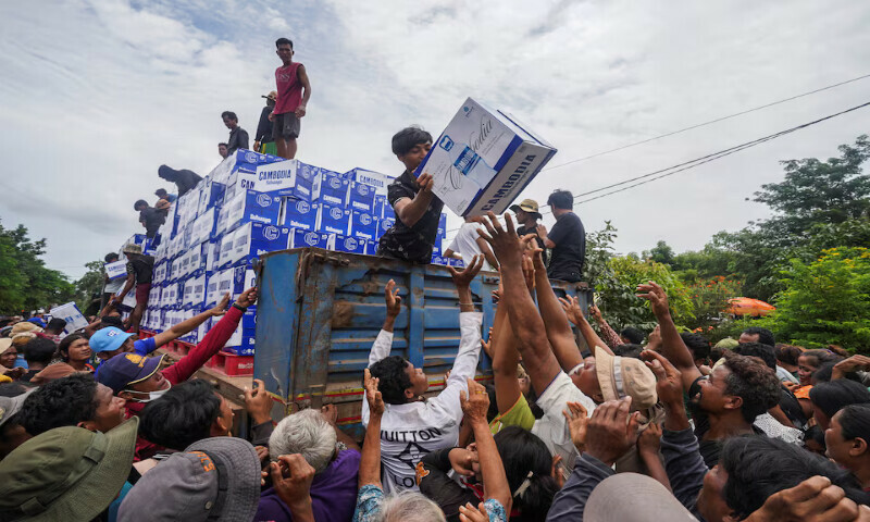 People gather to receive water supplies at Batthkao Primary School camp in Oddar Meanchey province, Cambodia. – Reuters